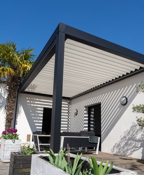 White louvered pergola shading a patio beside a palm tree