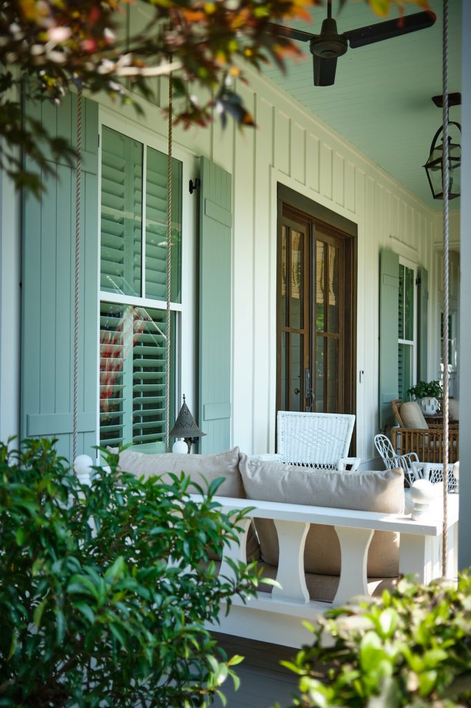 Board and batten shutters on a covered porch with plantation shutters inside the windows