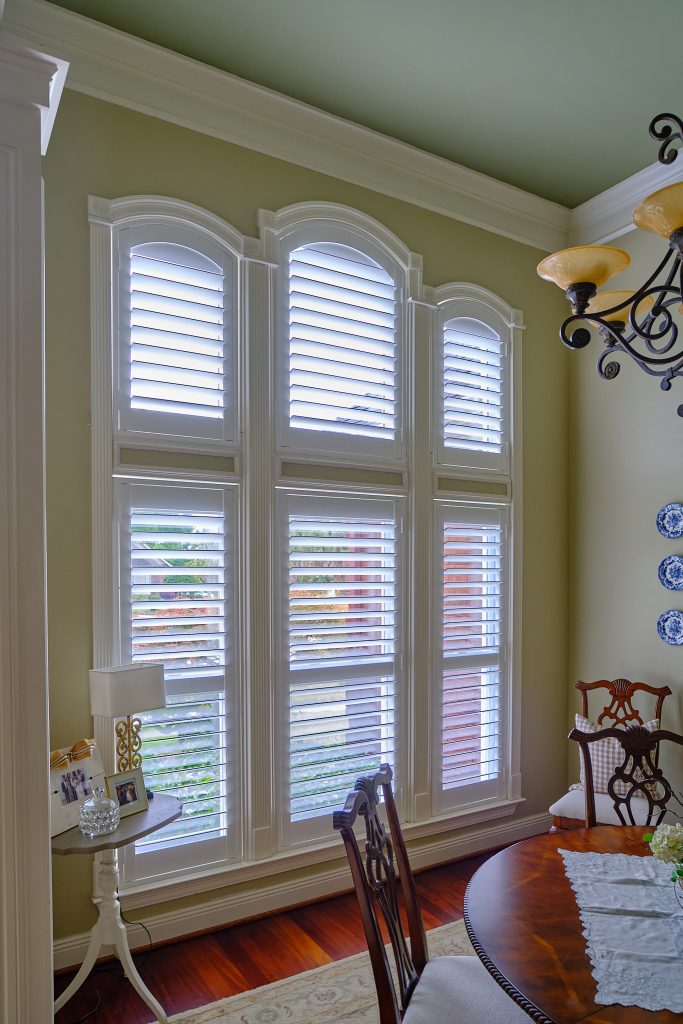 White arched plantation shutters on three windows in a Katy, TX dining room