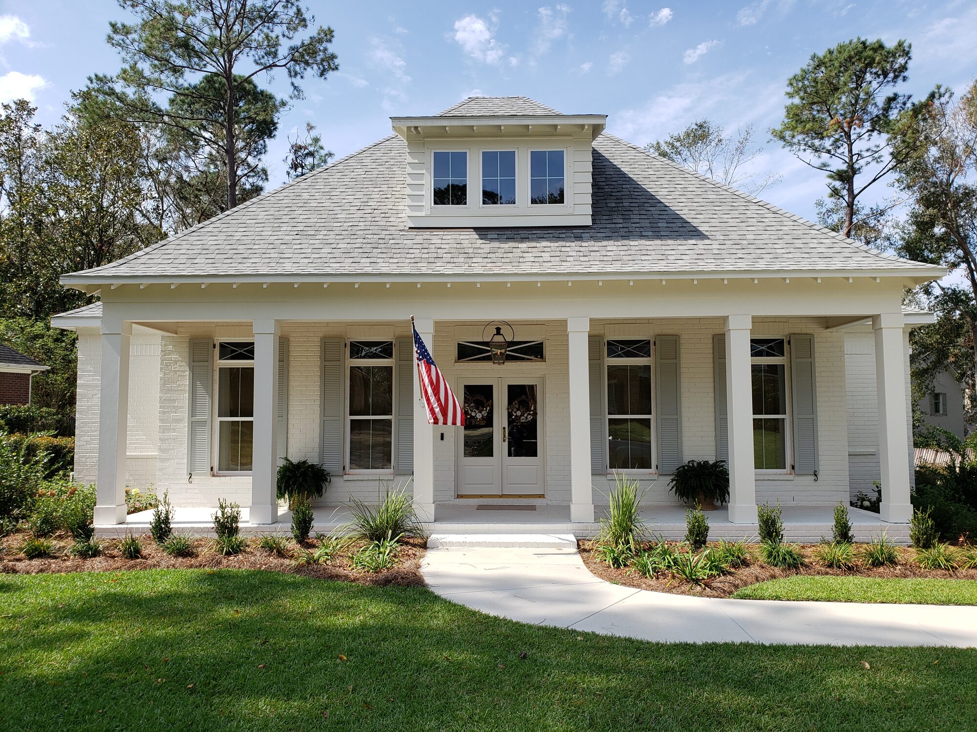 White suburban home with functional louvered exterior shutters and a covered front porch
